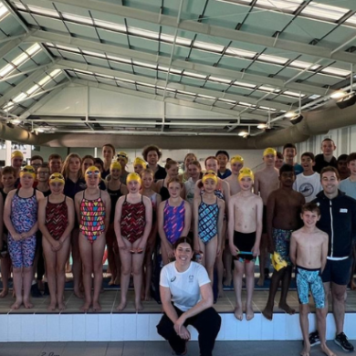 A group of people smiling and posing together in a swimming pool