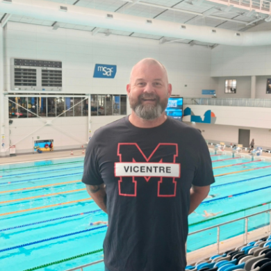 A man standing in a grandstand with a pool in the background