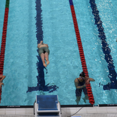 3 swimmers diving into the pool from above the blocks