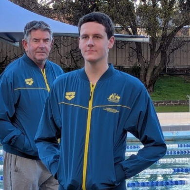A boy and man standing in front of an outdoor pool wearing green and gold tracksuits