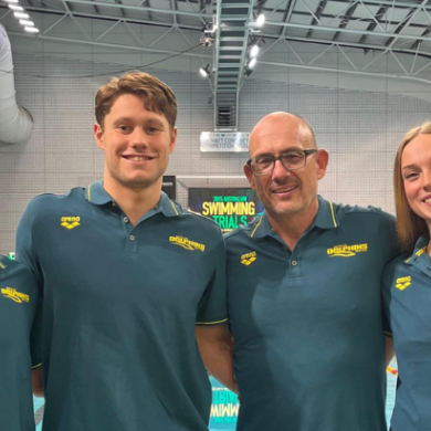 Four people stand in front of a pool for a photo